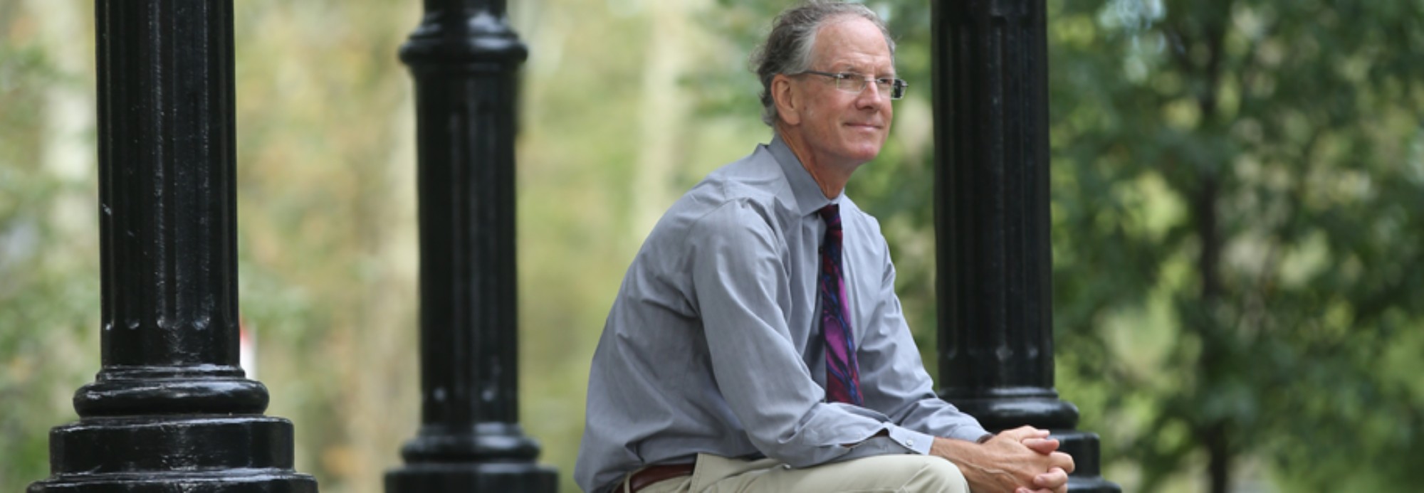David Hansen sits on a bench in the park.