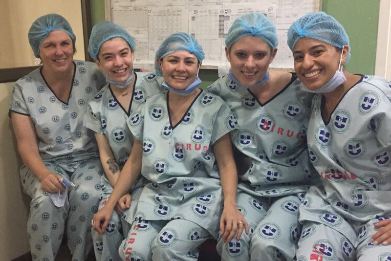 Students wear scrubs and pose together after a cleft palate surgery