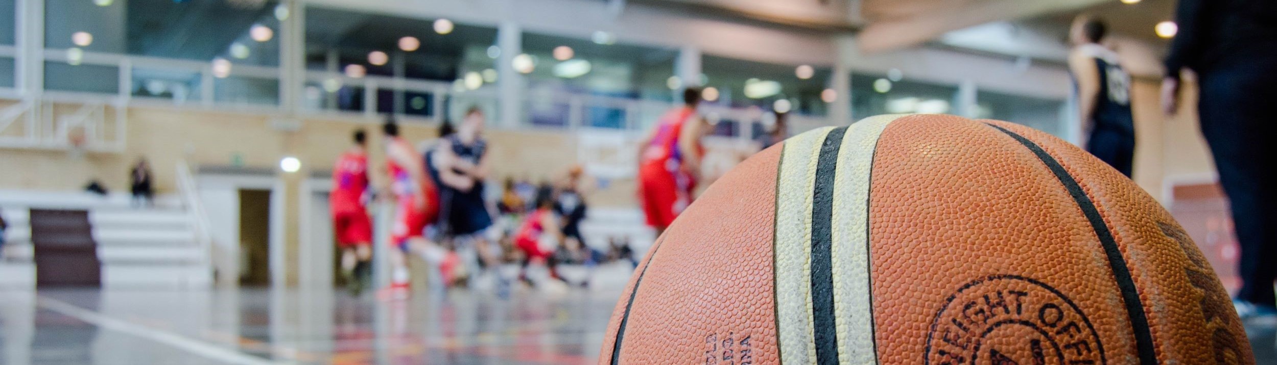 Basketball in a gym with players in the background.