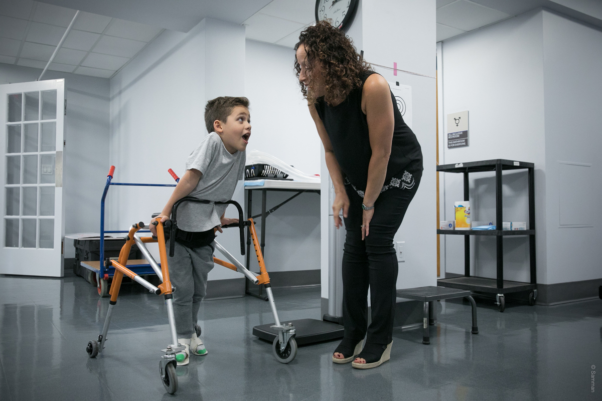 A PT works with a young boy on walking