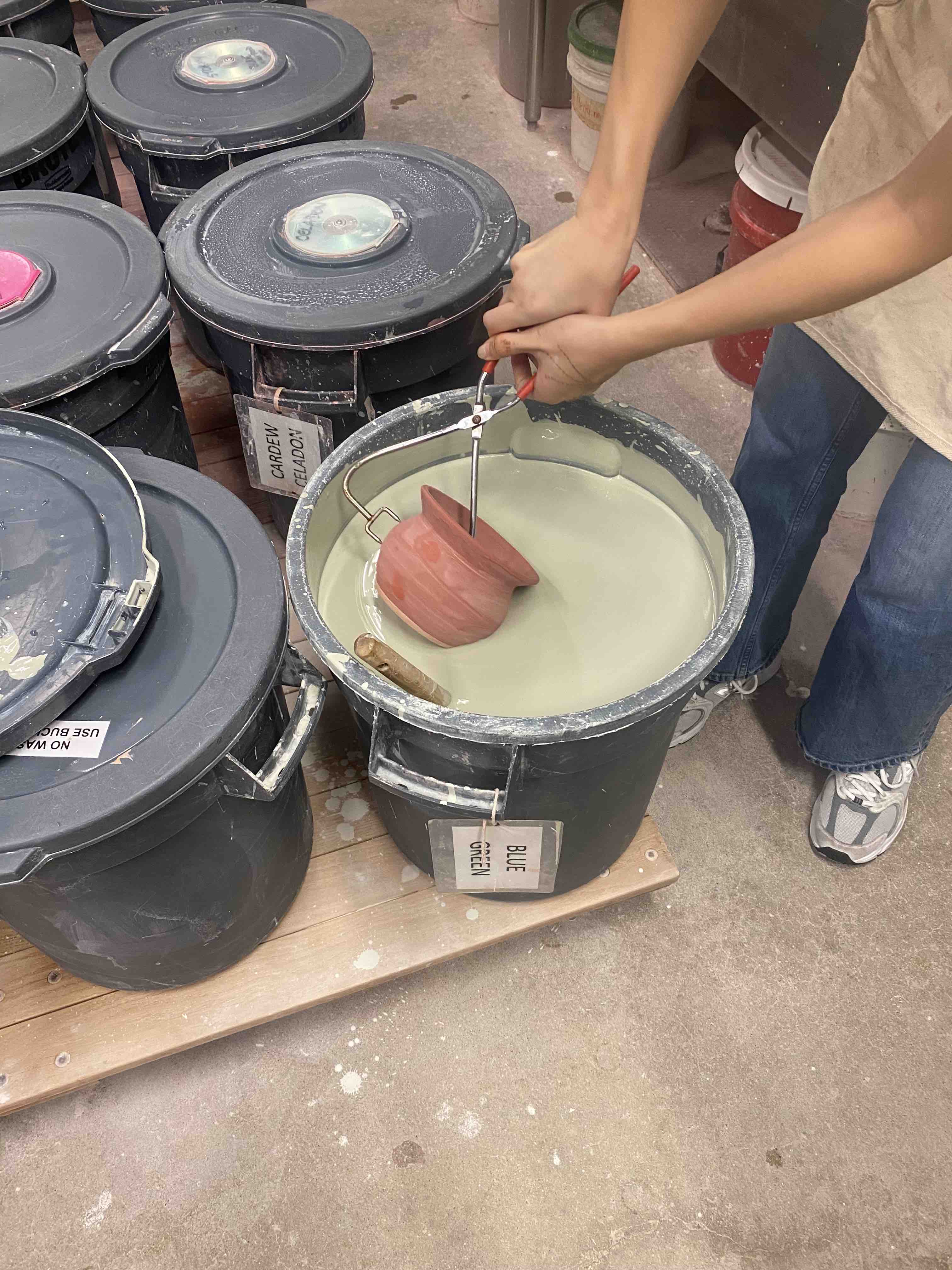 This image depicts a person glazing a ceramics piece.