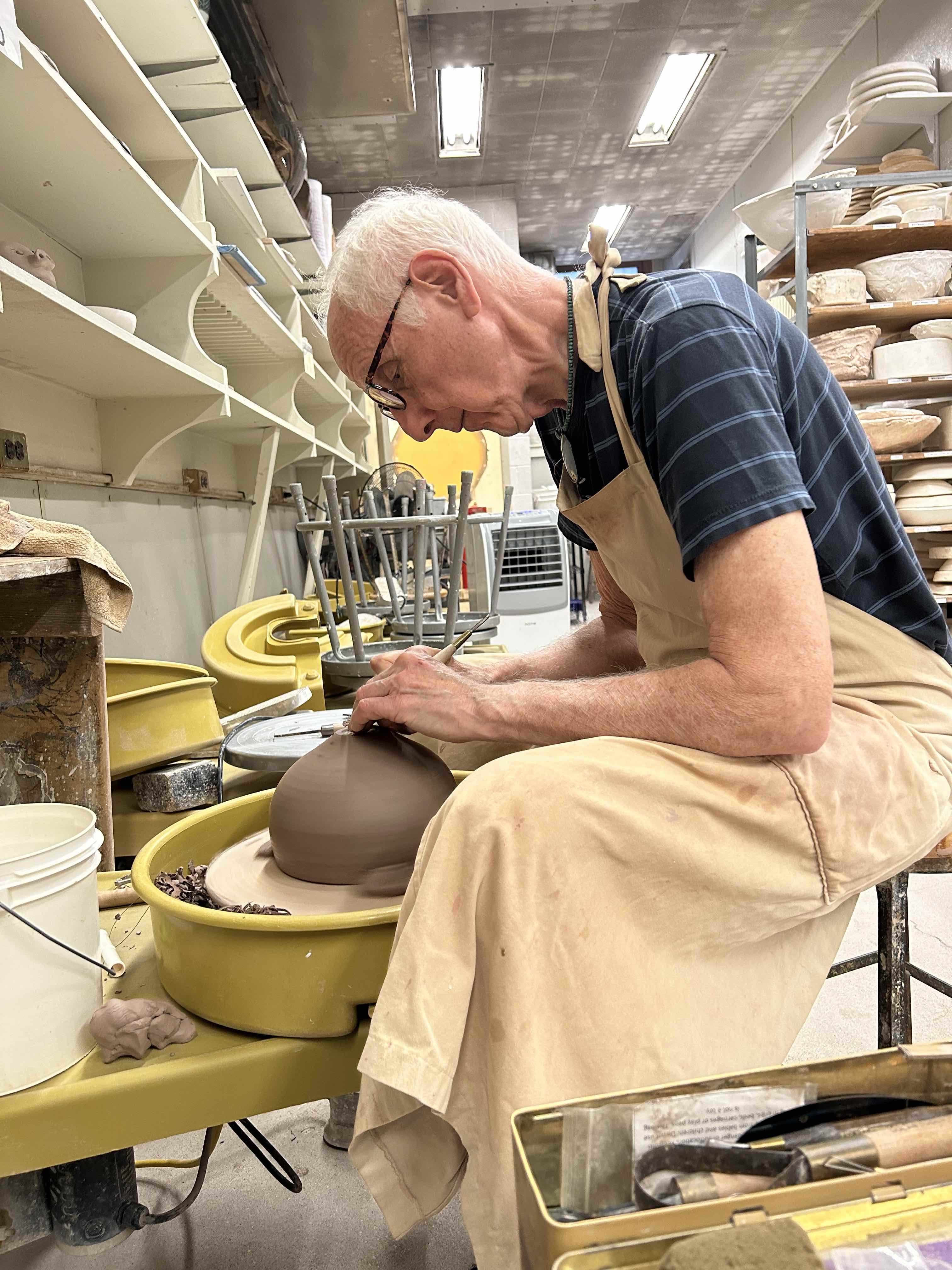 This picture depicts a man creating pottery on a pottery wheel