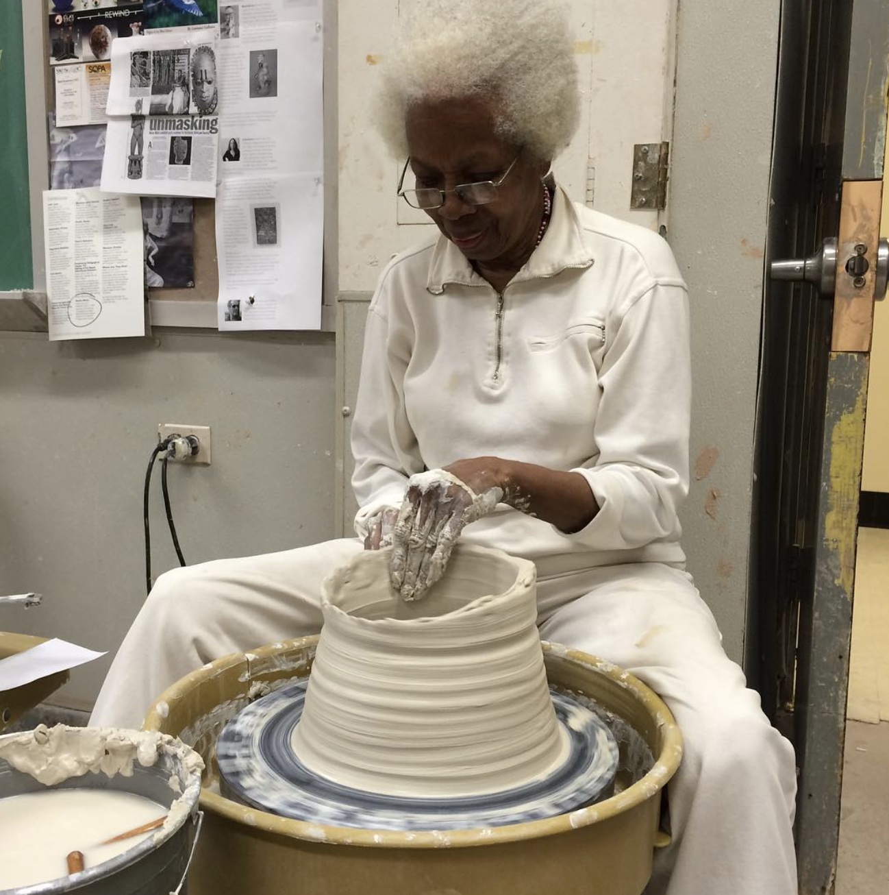 This picture depicts a woman creating pottery on a pottery wheel