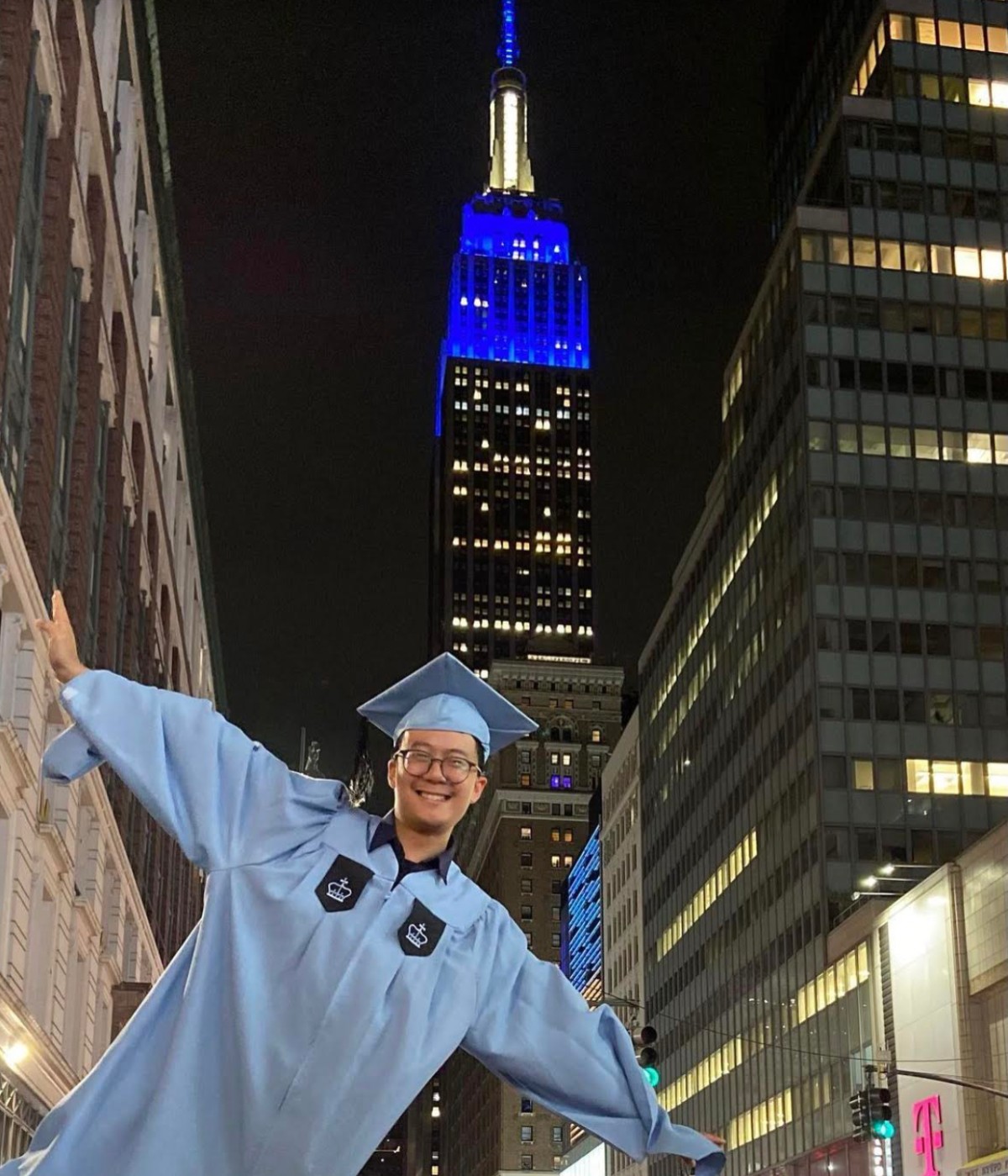 Student posing in front of the Empire State Building after Convocation