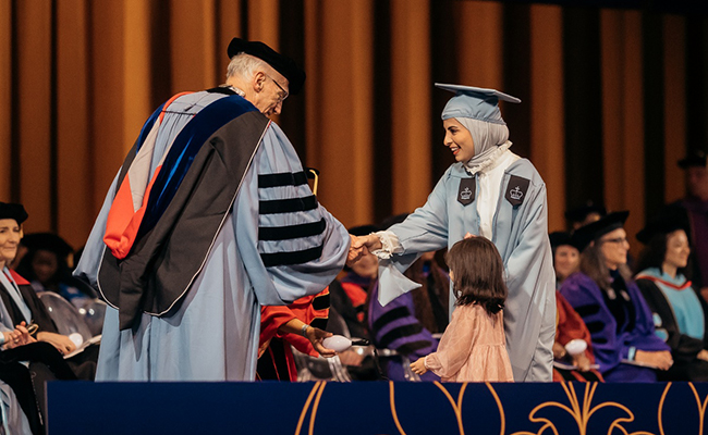 President Bailey shakes hands with a TC graduate