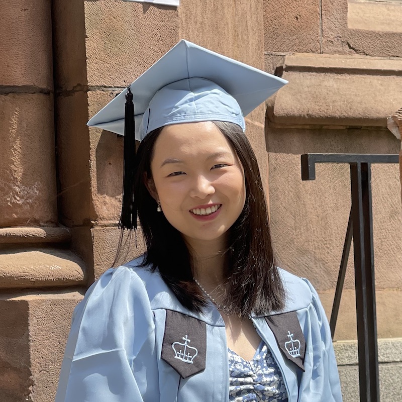 Yurou Lei smiling while dressed in Columbia blue graduate regalia
