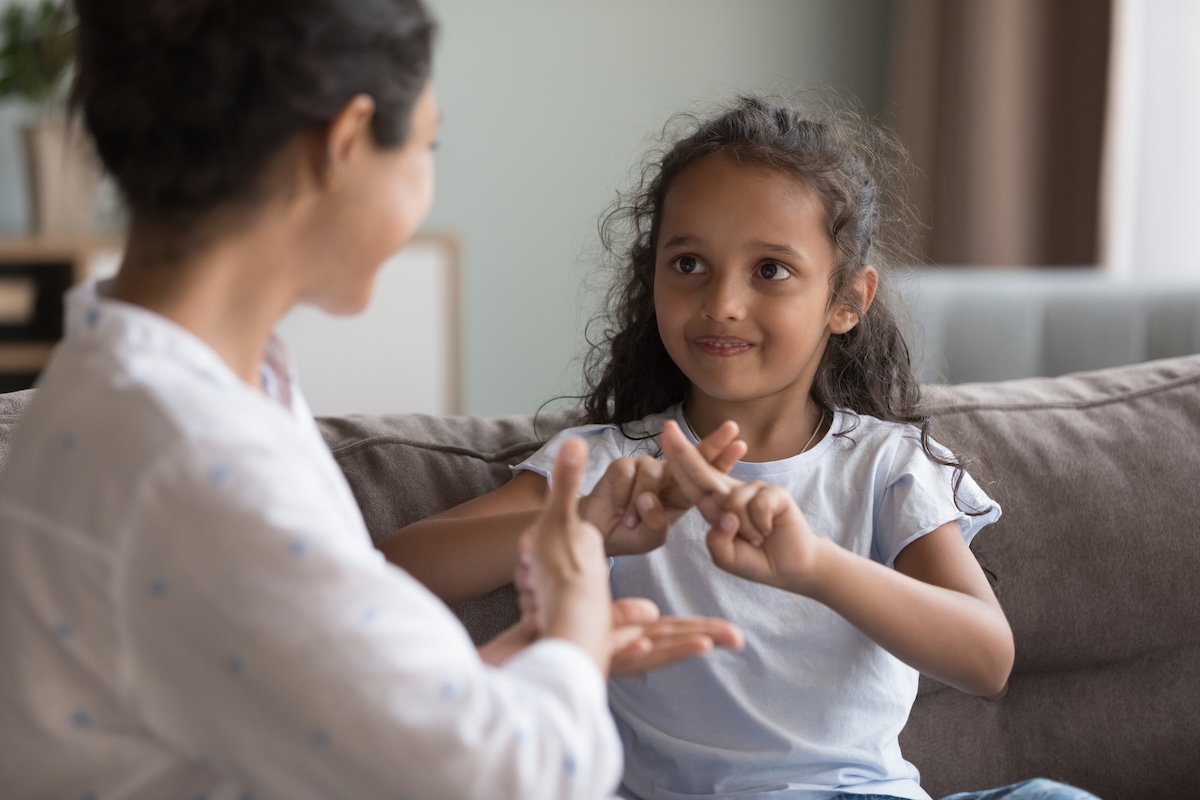 Girl doing sign language with adult