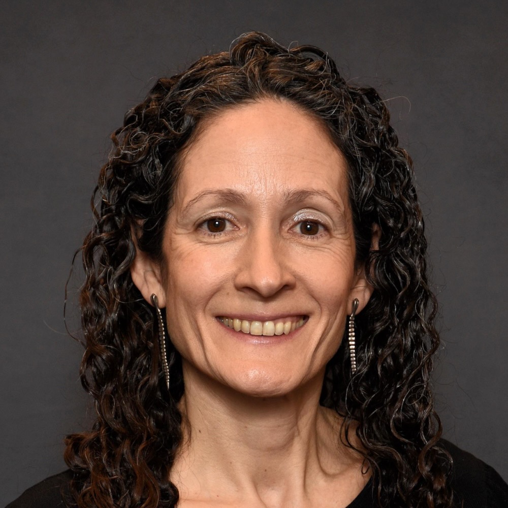 Patricia Martinez Alvarez, a woman with long, wavy brown hair, is smiling