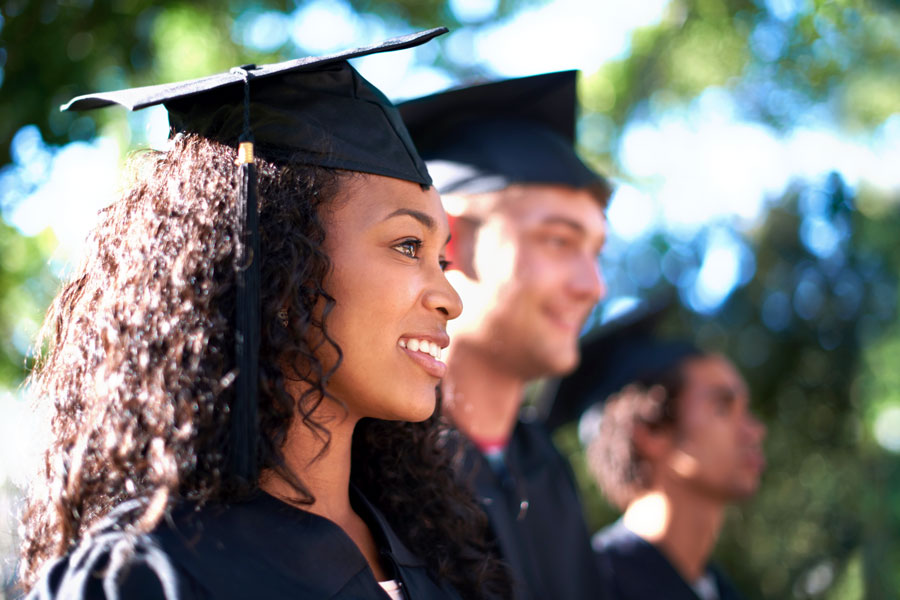 A community college student smiles while wearing her cap and gown