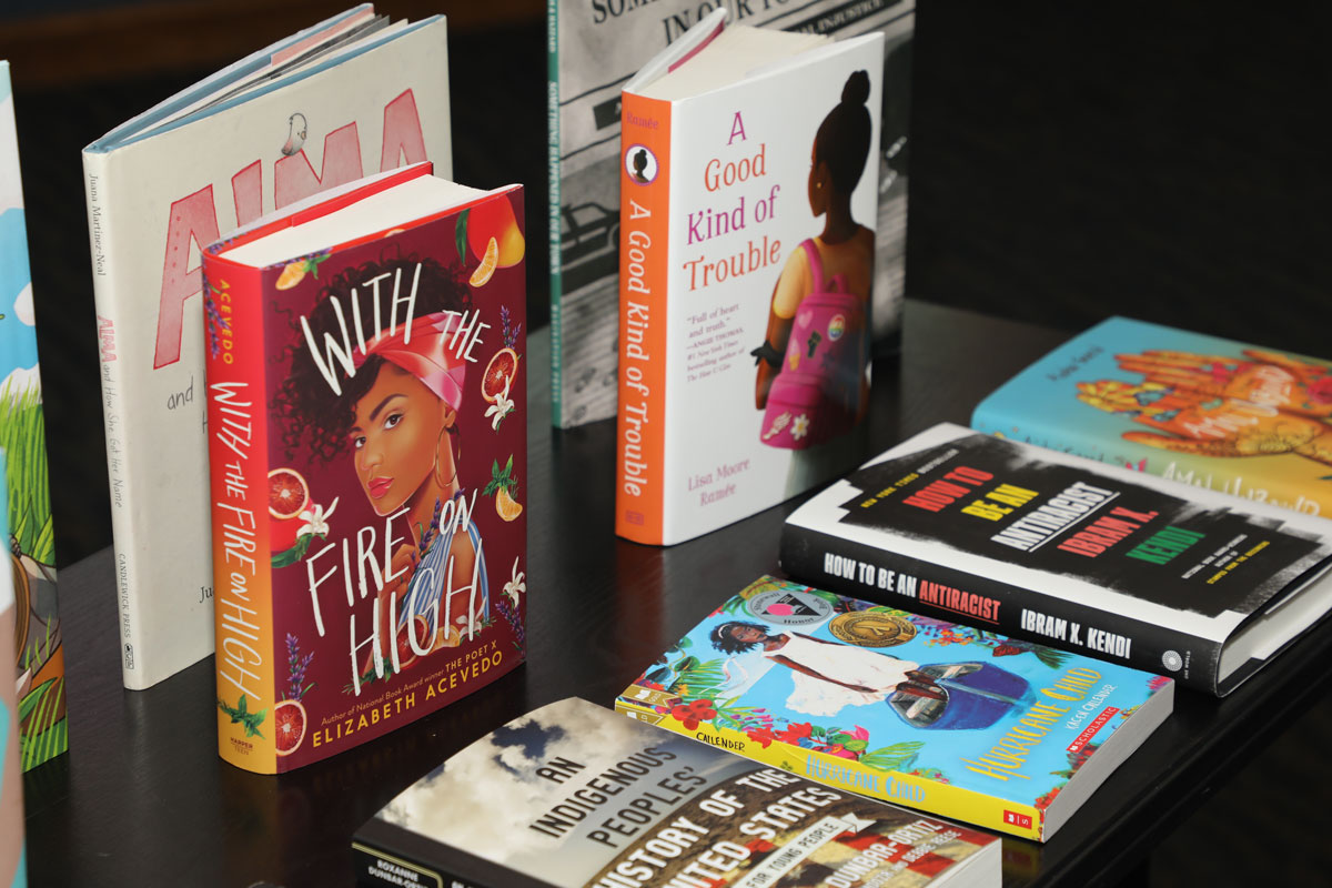 A series of children's books on a table: JUDGING BOOKS BY THEIR COVERS, TOO  The JustLit workshops are premised on a touchstone for multicultural education: Children need to see themselves reflected in the culture around them, both to develop a healthy sense of self and to feel the kind of connection and engagement that is essential to learning. 