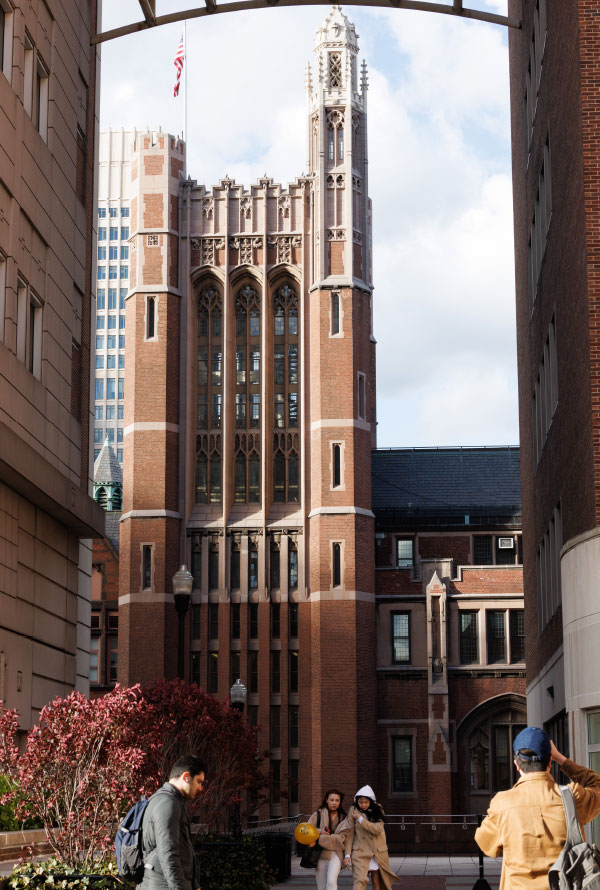 four people in the foreground with a gothic style building and tower in the backgound