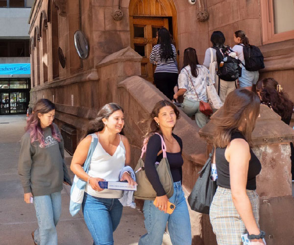 group of students walking up a few stairs and into a buliding