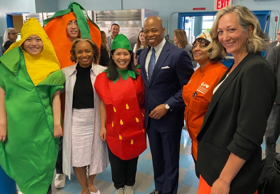 people wearing corn, carrot, and strawberry costumes, with four other people standing and smiling