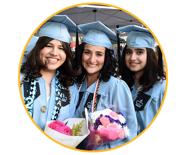 three people wearing graduation cap and cown holding flowers and smiling