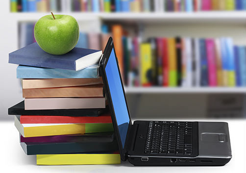 Laptop and books with apple on top